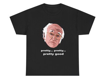 May include: Black t-shirt featuring a cartoon illustration of a man with glasses and white hair. The text "pretty... pretty... pretty good" is printed below the illustration. The shirt is made of a soft material.