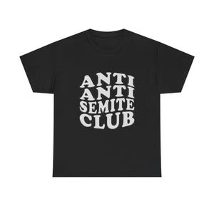 Könnte beinhalten: Schwarzes T-Shirt mit dem weißen Text "ANTI ANTI SEMITE CLUB" in einer gestapelten, wellenförmigen Schriftart. Das T-Shirt mit Rundhalsausschnitt ist ein lässiger Stil. Der Text ist mittig auf der Brust platziert.