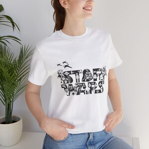 Może przedstawiać: Biała koszulka z czarno-białym nadrukiem logo Star Wars, złożonym z r&oacute;żnych postaci i przedmiot&oacute;w ze świata Gwiezdnych Wojen.