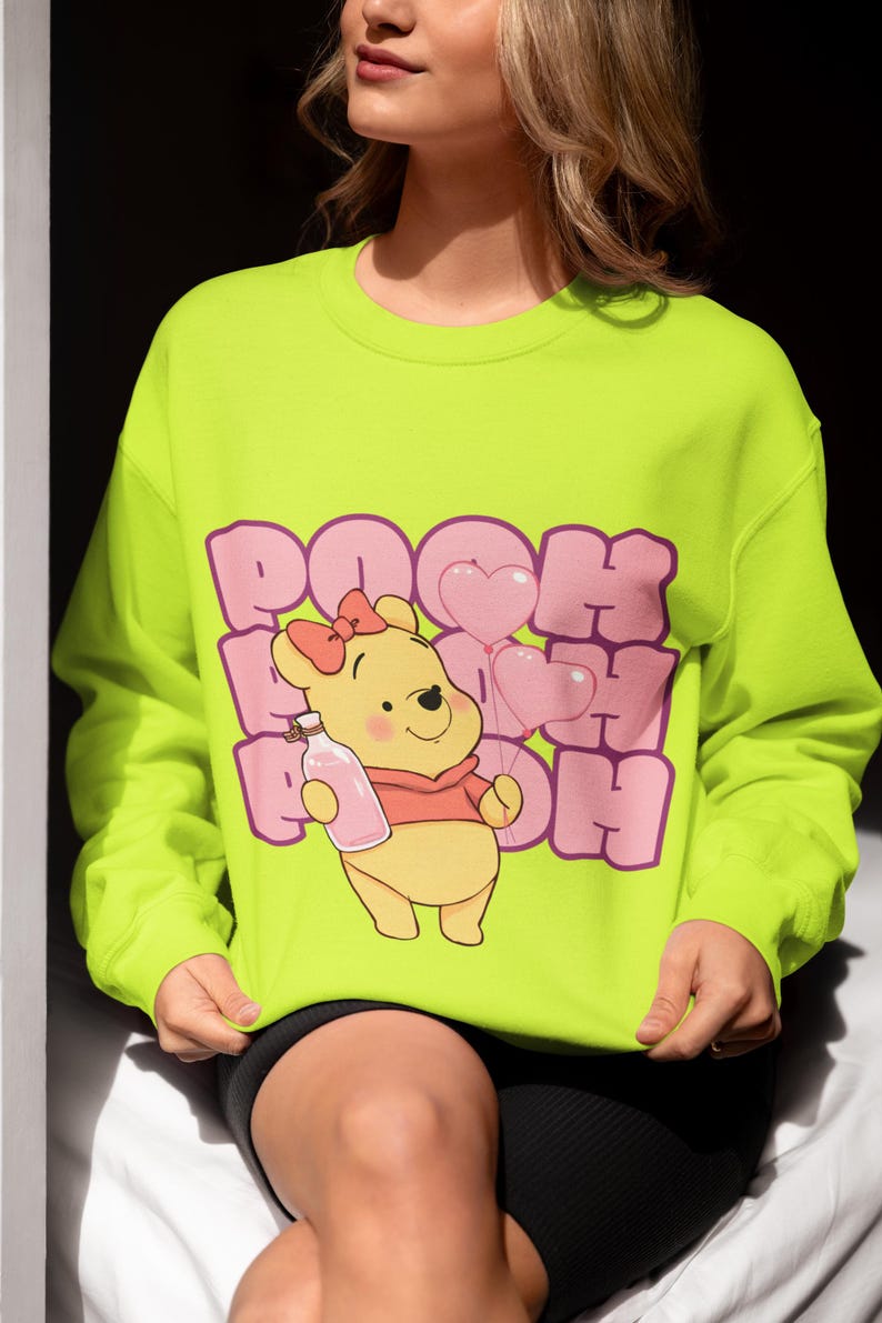May include: A bright yellow sweatshirt with a pink graphic of Winnie the Pooh holding a bottle and balloons. The text "POOH POOH POOH" is printed in pink.