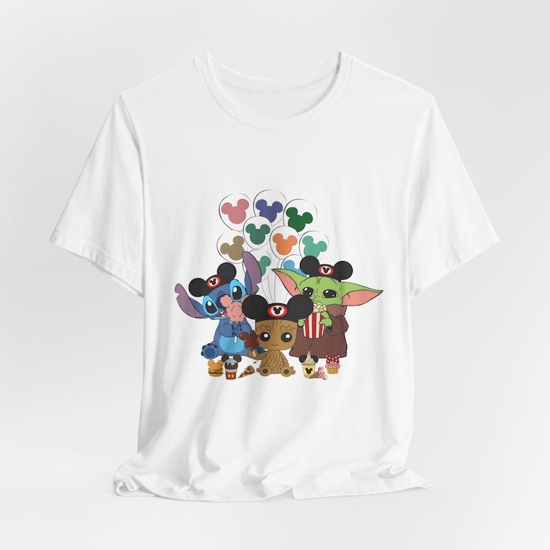 Puede incluir: Camiseta blanca con un estampado gr&aacute;fico de Stitch, Baby Yoda y Groot sosteniendo globos de Mickey Mouse. Los personajes llevan orejas de Mickey Mouse.