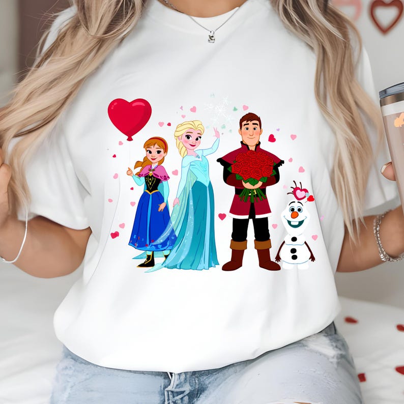 Pu&ograve; includere: T-shirt bianca con un design a cartoni animati dei personaggi del film Frozen. Il design include Anna, Elsa, Kristoff e Olaf, con un palloncino a forma di cuore rosso e cuori rosa sparsi.