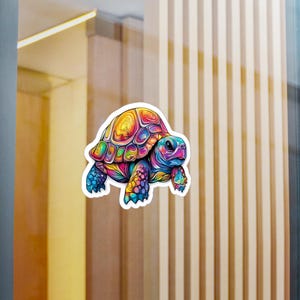 May include: A colorful sticker featuring a vibrant turtle illustration. The turtle's shell is a mix of yellow, orange, and red, while its body and legs are blue and purple. The sticker has a white border and is likely for decorative purposes.