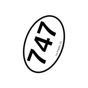 May include: White oval sticker with black text that reads "747 Los Angeles, CA".