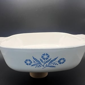 Puede incluir: Plato para hornear de cerámica blanca con diseño floral azul. El plato tiene dos asas y un fondo ligeramente redondeado.