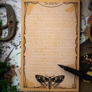 May include: A vintage-style lined notepad with a decorative border and a black and white moth illustration. The notepad has the word "Notes" printed at the top.