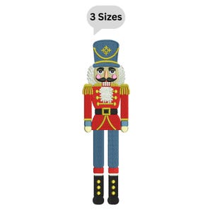 May include: Embroidered nutcracker in red, blue, and gold. The nutcracker has a white beard and mustache, and wears a blue hat. The text "3 Sizes" is in a speech bubble above the nutcracker.