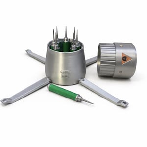 May include: A silver metal tool set. The central cylindrical component contains multiple pointed rods. The set includes a green and silver handled tool and several silver arms extending outwards. A cylindrical component with a hazard symbol is also present.