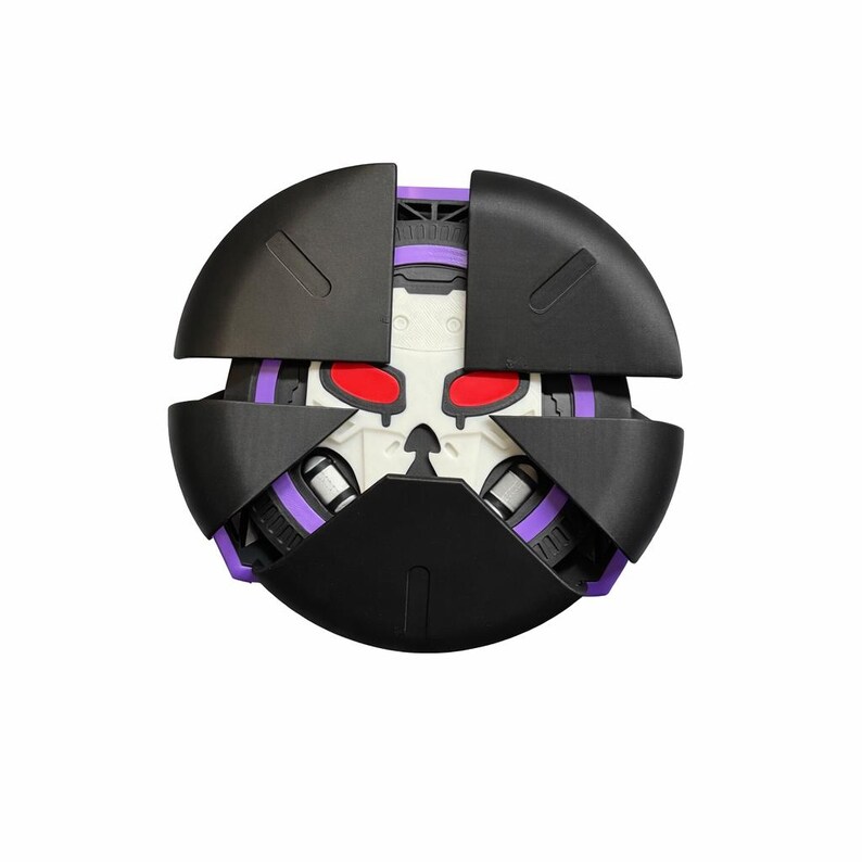 Puede incluir: Un juguete esf&eacute;rico negro y morado con un dise&ntilde;o de calavera. El juguete tiene un dise&ntilde;o segmentado con ojos rojos y detalles morados. El juguete es probablemente un objeto de colecci&oacute;n o un juguete para ni&ntilde;os.