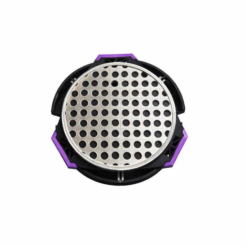 Puede incluir: Vista superior de un filtro de aire negro y plateado con un acento morado. El filtro tiene una pantalla met&aacute;lica perforada circular en el centro, rodeada por un marco de pl&aacute;stico negro. El acento morado est&aacute; en el borde exterior.