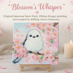 May include: A square painting on a small easel depicts a white bird with black accents perched on a branch with pink cherry blossoms. The painting is titled "Blossom's Whisper" and is described as an original Japanese Snow Fairy painting.