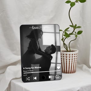 May include: A black and white photo of a couple in a digital photo frame with a music player interface. The music player is playing "A Song for Mama" by Boyz II Men. The text "love you" is displayed at the top of the frame.