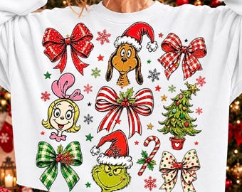 May include: A white long-sleeve sweatshirt featuring a colorful holiday-themed graphic print. The design includes illustrations of a green character, a blonde character, a Christmas tree, candy canes, and various patterned bows and snowflakes.