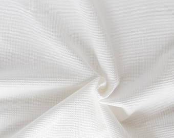 May include: White waffle-weave fabric with a textured surface. The fabric is folded and creased, creating a soft, drapey look.