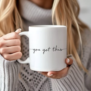 Op de afbeelding: Een witte keramische mok met een zwarte inscriptie die "you got this" luidt.