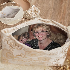 May include: A cream-colored zippered pouch featuring a gold floral pattern on the exterior. The interior lining displays a printed photograph of a woman and a child, with an inset showing the text I Love You Mom and a small floral illustration.