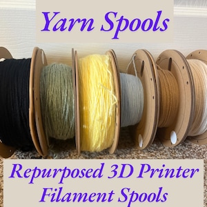 Puede incluir: Seis carretes de filamento de impresora 3D reutilizados llenos de hilo de varios colores: negro, verde oliva, amarillo, gris claro, beige y blanco. El texto "Yarn Spools" y "Repurposed 3D Printer Filament Spools" es visible.