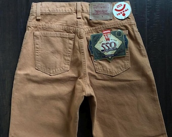 Puede incluir: Un par de pantalones vaqueros Levi's 550 Relaxed Fit de color marrón con una etiqueta de Levi's en el bolsillo trasero.
