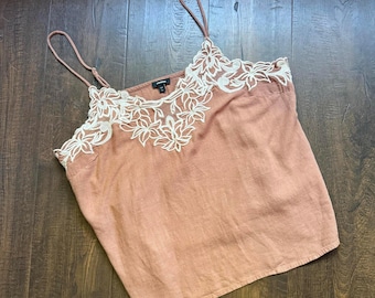 May include: A dusty rose camisole with delicate spaghetti straps and a floral lace trim along the neckline. The top is made of a soft, lightweight fabric and is a solid color. The camisole is a casual top.
