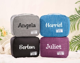 May include: Four personalized travel organizers in gray, blue, black, and purple. Each case has a name printed in white, with a small graphic of electronic devices. The cases are rectangular with a handle.