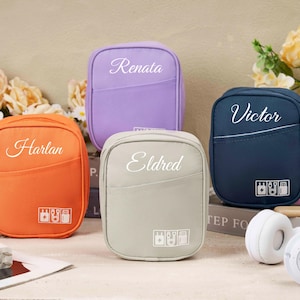 Puede incluir: Cuatro pequeñas bolsas de viaje rectangulares en naranja, lavanda, gris y azul marino. Cada bolsa tiene un nombre impreso en escritura cursiva: Harlan, Renata, Eldred y Victor. Cada bolsa tiene un pequeño bolsillo y un gráfico de iconos de dispositivos electrónicos.