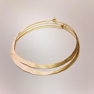 May include: A pair of gold hoop earrings with a hammered finish. The earrings are simple and elegant, and would make a great gift for any occasion.