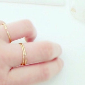 Puede incluir: Dos anillos de oro en un dedo. Los anillos son simples y delicados, con una forma ligeramente curvada.