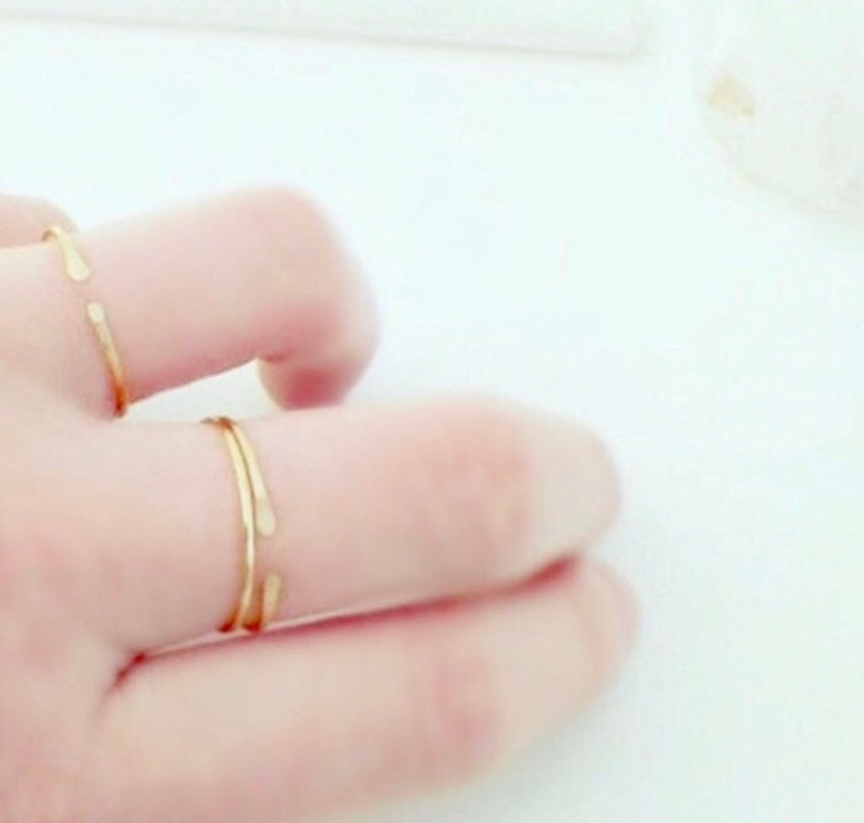 Puede incluir: Dos anillos de oro en un dedo. Los anillos son simples y delicados, con una forma ligeramente curvada.