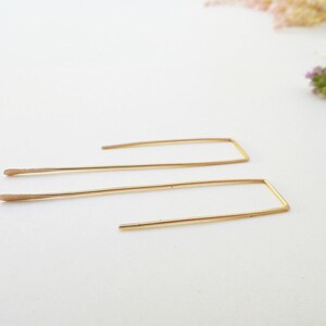 May include: A pair of gold-toned rectangle shaped earrings with a thin wire design.