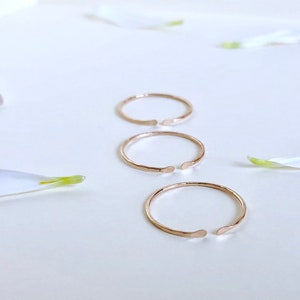 Puede incluir: Tres anillos abiertos de color dorado sobre una superficie blanca. Los anillos est&aacute;n hechos de metal fino y tienen una textura ligeramente martillada.