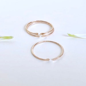 Puede incluir: Dos anillos de color dorado con acabado martillado. Los anillos son abiertos y tienen una forma ligeramente curvada.