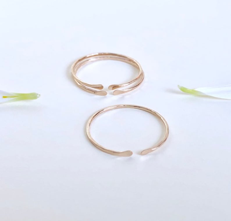Puede incluir: Dos anillos de color dorado con acabado martillado. Los anillos son abiertos y tienen una forma ligeramente curvada.
