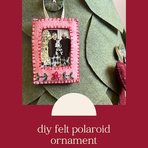 May include: A pink felt polaroid ornament with a photo of a family of three inside. The ornament is decorated with red stitching and a small red heart.