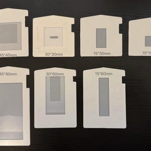 Può includere: Un set di otto modelli in plastica bianca con ritagli rettangolari di diverse dimensioni. I modelli sono etichettati con le loro dimensioni in millimetri, come 45x45mm, 30x30mm, 15x30mm, 15x15mm, 45x90mm, 30x60mm e 15x60mm.