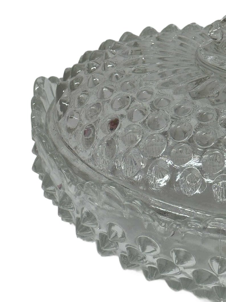 May include: Clear glass candy dish with a textured, bubble-like pattern on the lid and base. The edges of the dish have a scalloped design. The dish is likely vintage and suitable for decorative use.