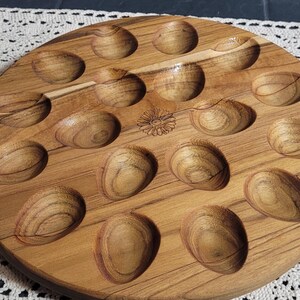 May include: A wooden egg tray with 18 individual indentations for holding eggs. The tray is made of light brown wood with a natural grain pattern.