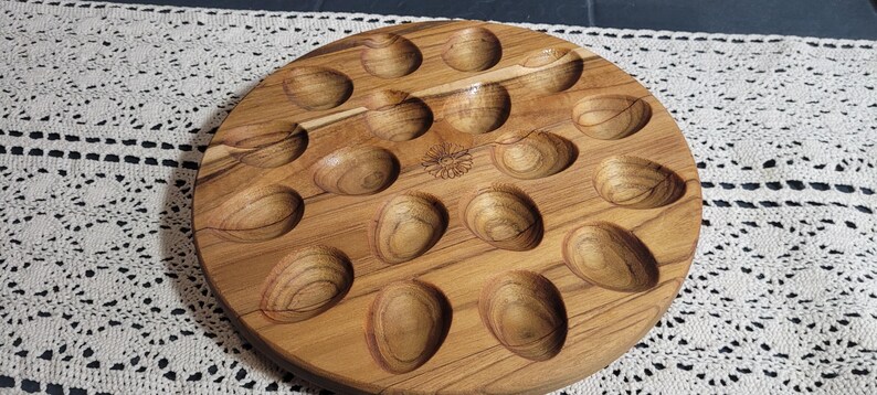 May include: A wooden egg tray with 18 individual indentations for holding eggs. The tray is made of light brown wood with a natural grain pattern.