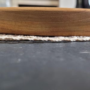 May include: A round wooden serving tray with a natural wood finish. The tray has a slightly raised edge and is made of solid wood.
