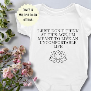 May include: White baby onesie with black text that reads "I just don't think at this age, I'm meant to live an uncomfortable life." A black lotus flower graphic is below the text.