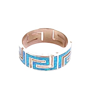 May include: A silver ring with a Greek key design. The ring features a band of bright blue inlay, creating a striking contrast against the silver. The design is a repeating geometric pattern, adding a touch of classic elegance.