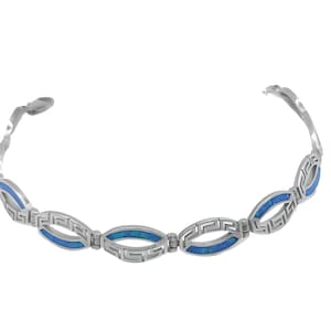 Könnte beinhalten: Ein silbernes Armband mit griechischem Schlüsselmuster. Das Armband hat ovale Glieder mit blauem Inlay. Das Armband ist offen und kann getragen werden. Das Armband befindet sich auf weißem Hintergrund.