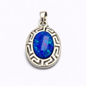 Puede incluir: Colgante de plata con una piedra preciosa ovalada azul. La piedra preciosa está rodeada por un diseño de llave griega plateada. Tiene un pequeño lazo en la parte superior para una cadena.