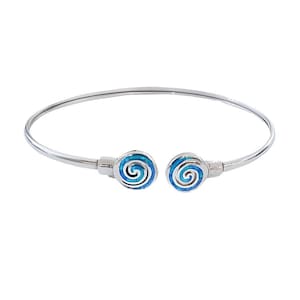 Puede incluir: Una pulsera de brazalete plateada con un diseño en espiral. La pulsera presenta dos extremos circulares con un patrón de espiral azul y plateado. La pulsera es abierta y tiene un diseño simple y elegante.
