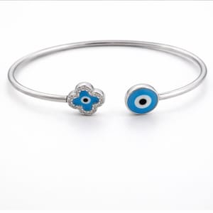 May include: A silver-toned bangle bracelet with two charms. One charm is a blue and white evil eye design, and the other is a blue and white clover design with clear crystals. The bracelet is open-ended.