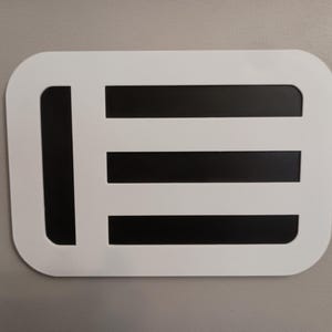 May include: A white rectangular design with rounded corners, featuring a black vertical bar on the left and three horizontal black bars. The design is set against a neutral gray background.