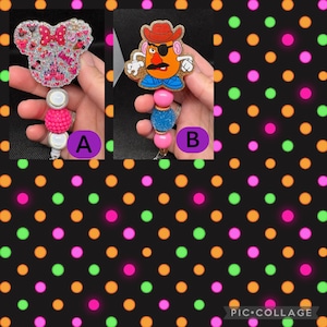May include: Two retractable badge holders. One features a Minnie Mouse design with a pink bow and castle. The other has a Mr. Potato Head design with a cowboy hat. Both have beaded accents in pink and blue.