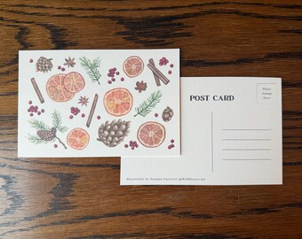 May include: A postcard with a watercolor illustration of orange slices, cinnamon sticks, pine cones, and berries. The postcard is next to a blank postcard with the words "POST CARD" printed on it. The artwork is signed "Watercolor by Autumn Universe @Wildhearts.Art."