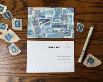 May include: A rectangular postcard featuring a collage of various blue vintage postage stamps, paired with a blank white postcard with the text POST CARD and a thin black pen. Several loose blue postage stamps are scattered around the cards.