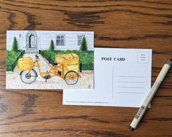 May include: A postcard featuring a watercolor illustration of a yellow Deutsche Post cargo tricycle parked on a cobblestone path in front of a white building with green hedges. The reverse side shows the text POST CARD and Place Stamp Here.