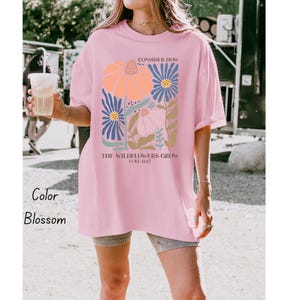 K&ouml;nnte beinhalten: Rosafarbenes Oversize-T-Shirt mit einem floralen Motiv und dem Text "Consider how the wildflowers grow Luke 12:27".